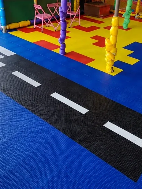 Faixa de pedestres e pista de carrinhos recortadas em piso modular azul