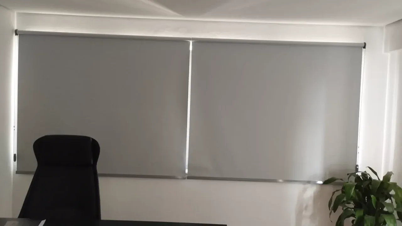Persianas rolo blackout cinza instaladas em escritório
