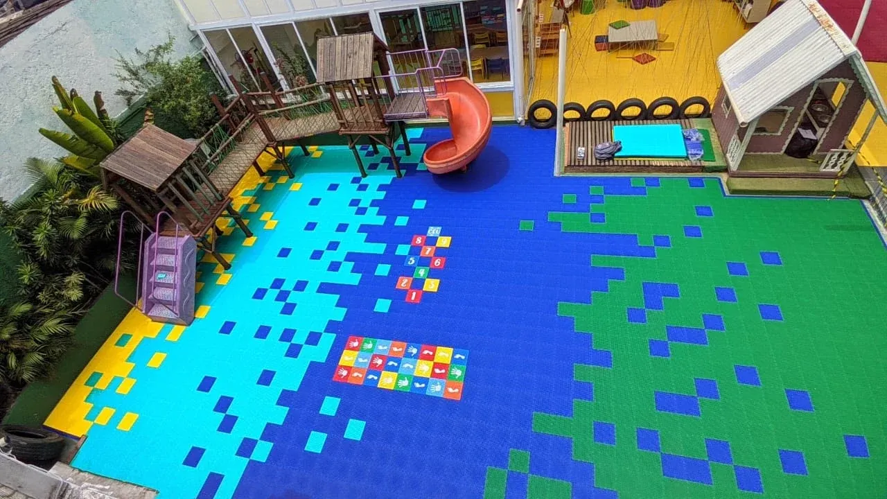Vista aérea de playground com piso modular azul, verde e amarelo