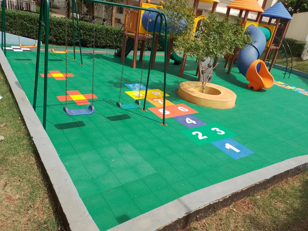 Pista de carrinhos e amarelinha numerada em piso modular em área de lazer
