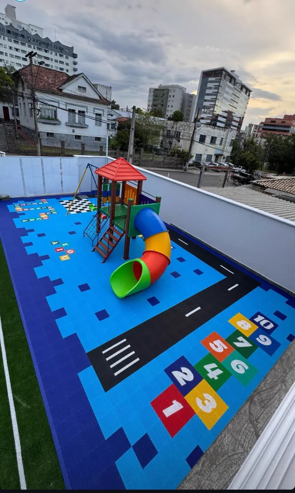Tobogã sobre piso modular azul em área de recreação coberta