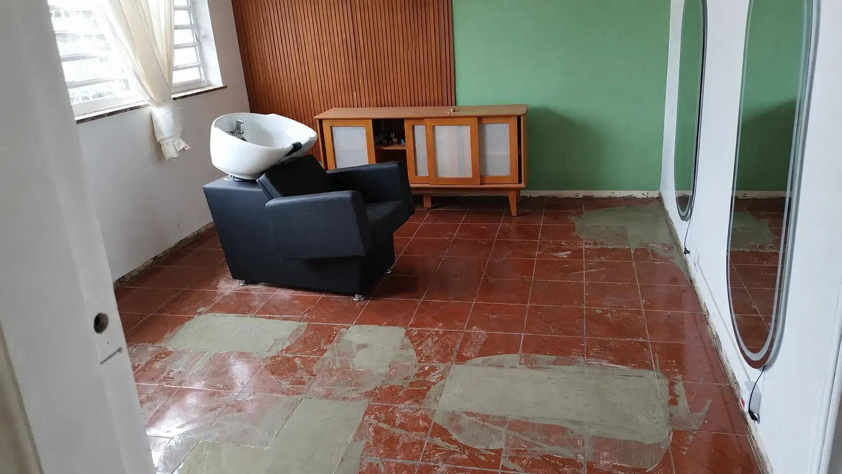 Salão com piso cerâmico desgastado e manchas de cimento, antes da instalação do piso laminado